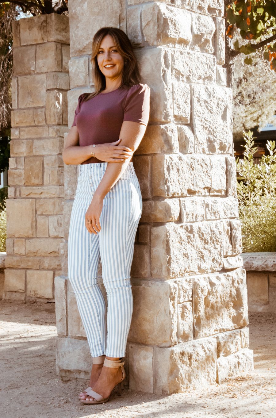 Rachel McGonigle leaning against a stone pillar, smiling
